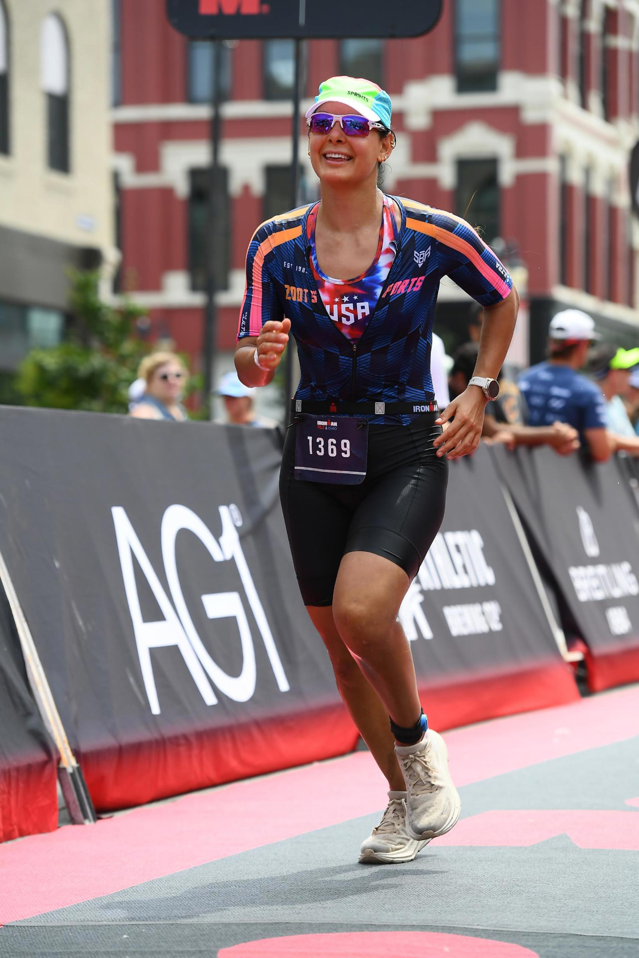 An athlete running toward the finish of a race past cheering crowds.